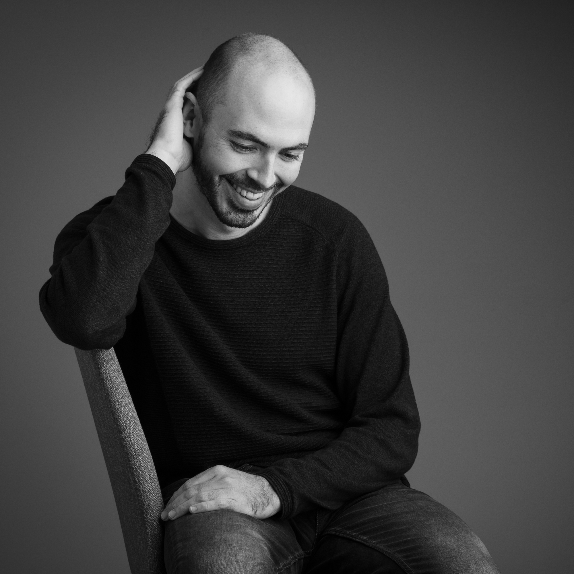 Authentieke zwart-witfoto van een zittende mental coach Jeroen Vanbever met een oprechte lach