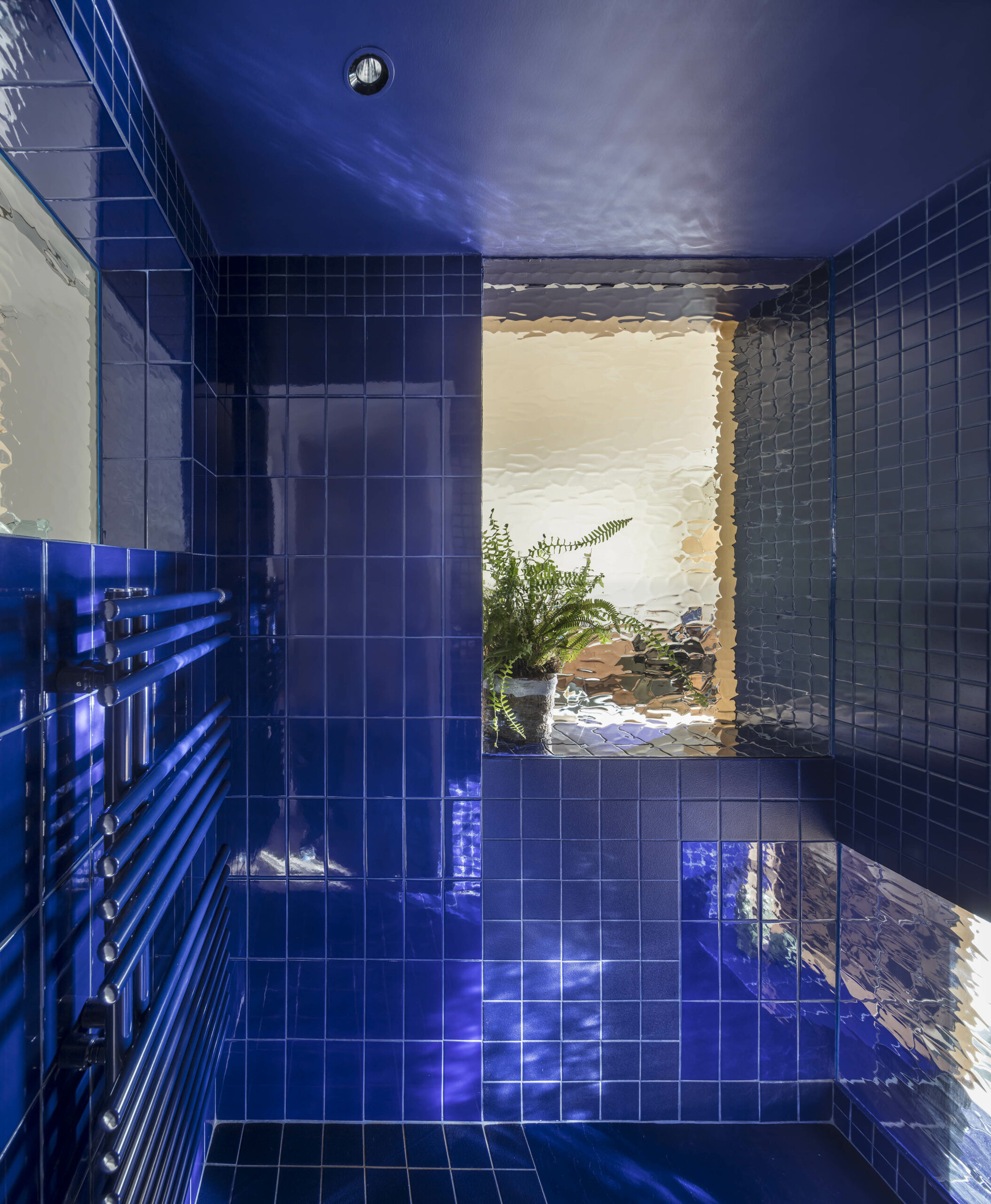 Daylight enters blue-tiled bathroom