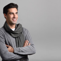 Handsome man wearing winter clothes smiling on white background. Young male with swater and scarf. Studio shot