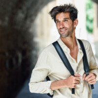 Young man sightseeing enjoying the streets of Granada, Spain. Male traveler carrying backpack in urban background.