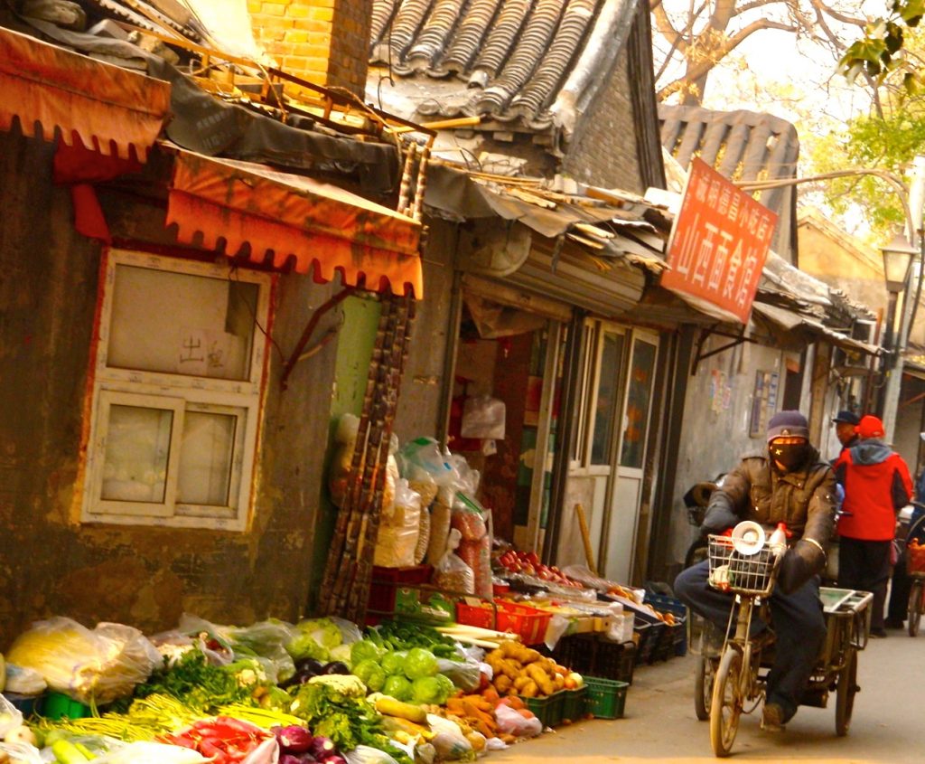 Gatuförsäljning en en hutong i Peking men med en dörr öppen in till dne lilla butiken.