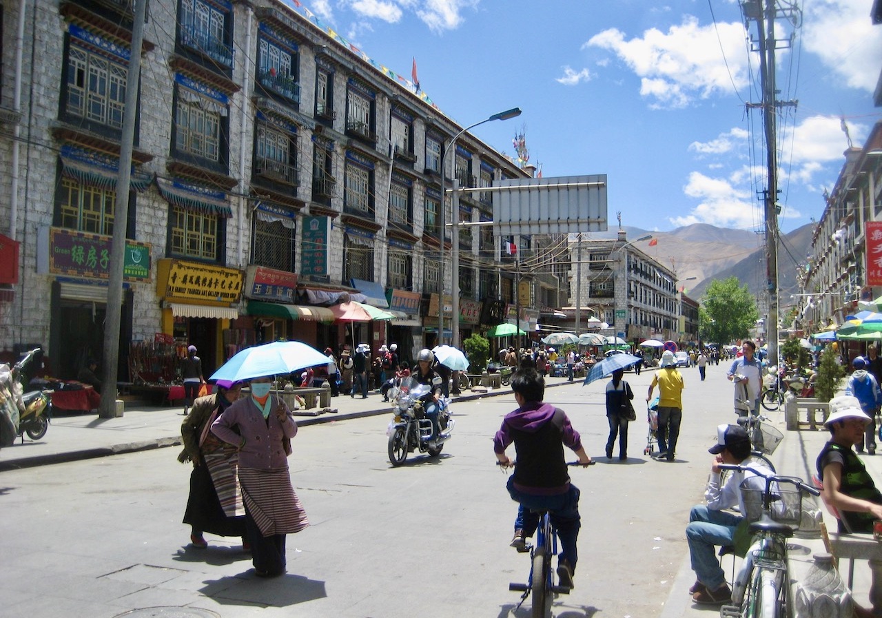 Lhasa. Typisk gatumiljö. Människor är klädda både i traditionella kläder och mer västerländska. 