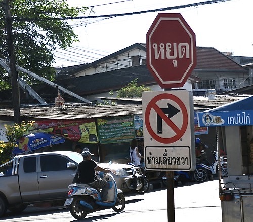 Thailand. Och jubileum i Skyltsöndag; idag # 400. Här en av min allra första skyltar. Från en thailändsk by. Och jag tar fotot i farten sittandes bakom maken på scootern. 