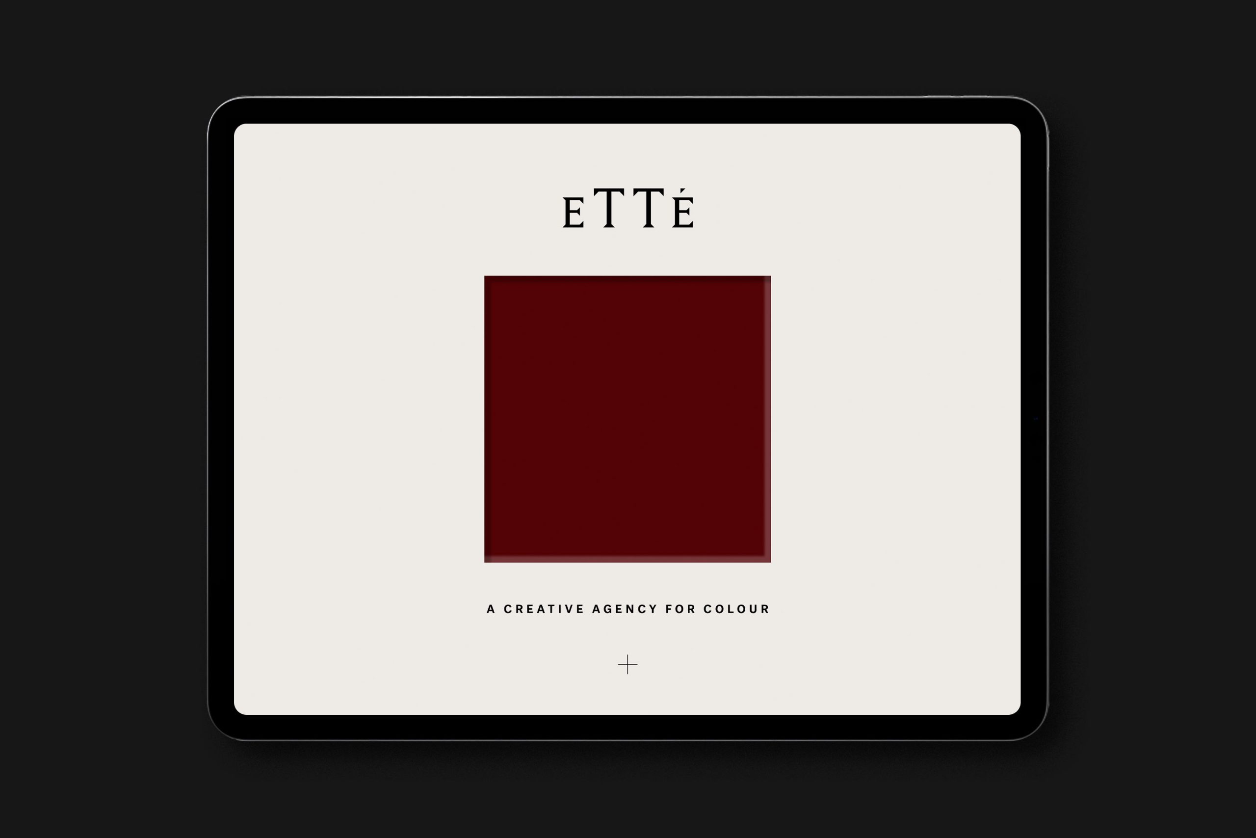 A tablet device photographed on a black background showcasing the website design for Etté as shown with a claret red square