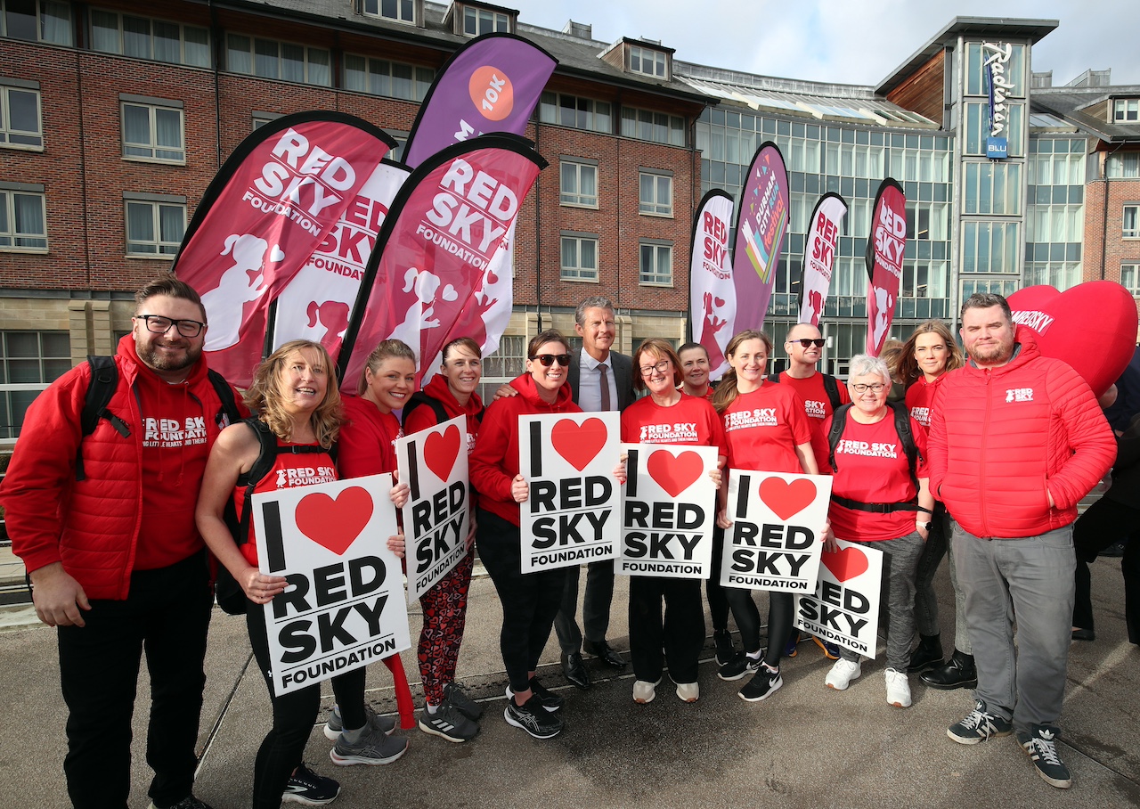 A group of people holding signs saying 'Red Sky' in front of the Radisson Blu Hotel Durham.