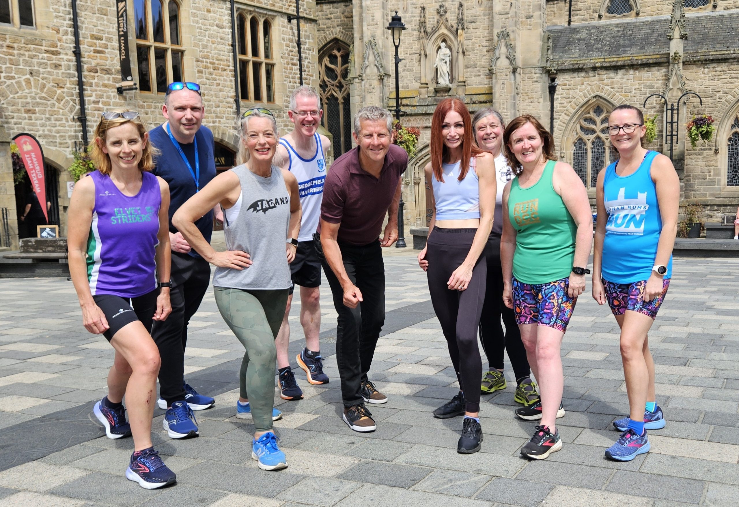 Eight people posing in running kit.