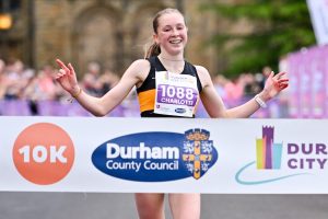 Runner with arms in the air as they cross the finish line at Durham City Runs. 