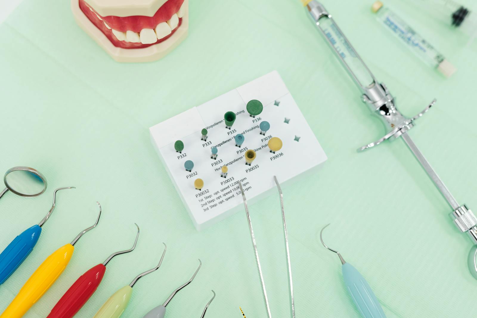 A close-up of dental tools and a jaw model on a green background, ideal for dentistry themes.