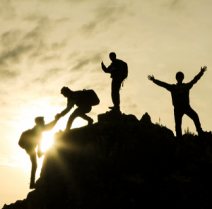 4 mænd hjælper hinanden op af et bjerg, udstråler livsglæde