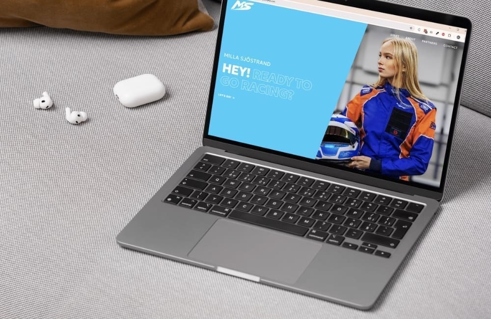 Milla Sjöstrands webbplats för racingförare visad på en MacBook, med personligt varumärke inom motorsport i cyan hero-sektion och fet typografi.