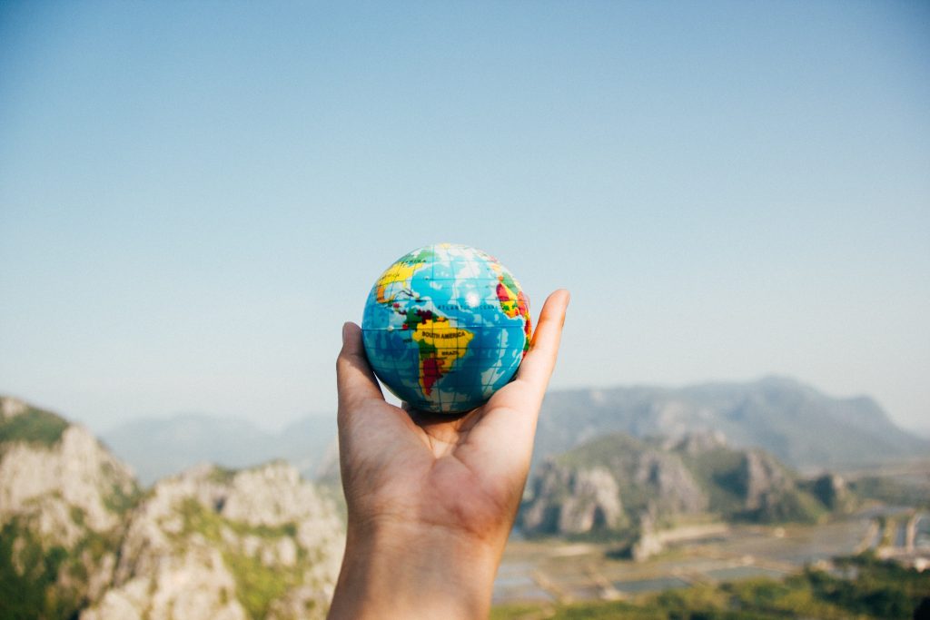 Esperiment Hello World Hand Holding a globe on a sunny day with mountains in the background