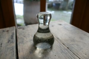 En antik støder af glas til at rive farve, ca. 9 cm høj.