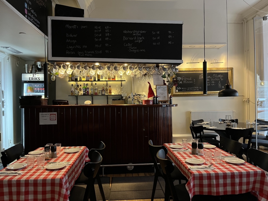 Välkomnande matsal med vy mot kassa och bar – Inbjudande atmosfär i denna stabila restaurang till salu i Malmö.