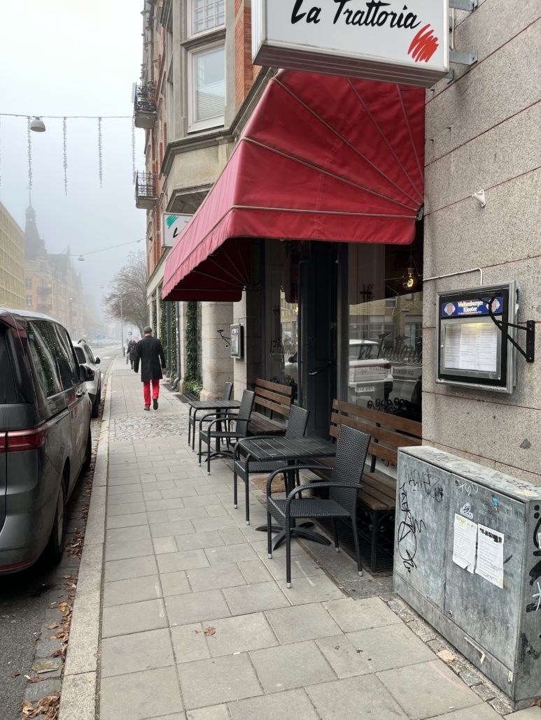 Exteriör bild av anrika La Trattoria – Populär restaurangöverlåtelse i Malmö med solig uteservering på höger sida.