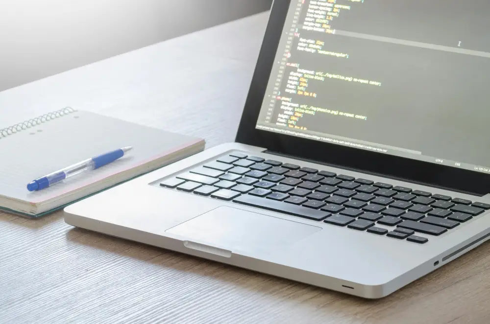 Ordinateur portable affichant du code avec un stylo sur le bureau