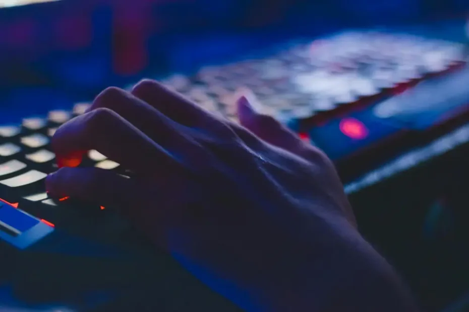 Main sur un clavier rétroéclairé dans un environnement informatique, illustrant le domaine de l’IT