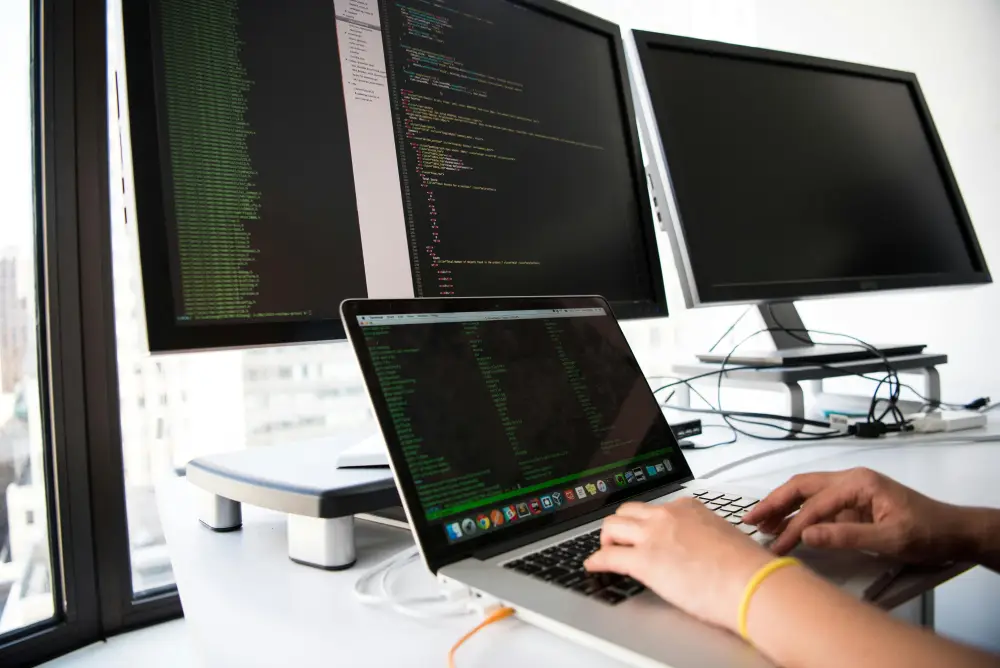 Développeur travaillant sur plusieurs écrans avec du code informatique