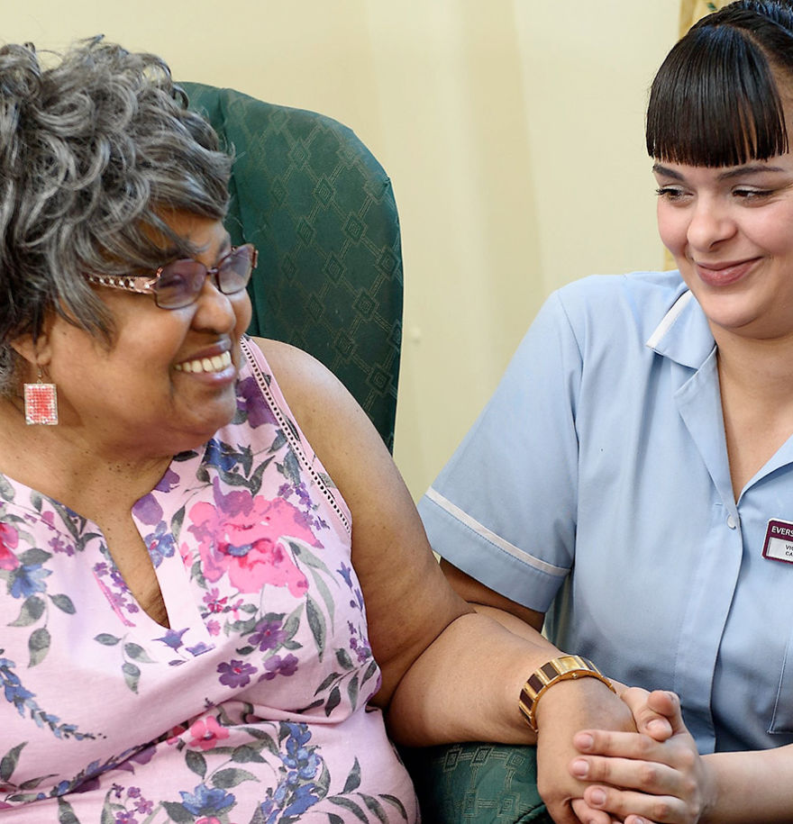 team member holding the hand of a female resident and smiling