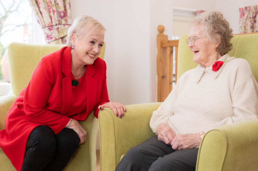 resident and family member sitting down and laughing together