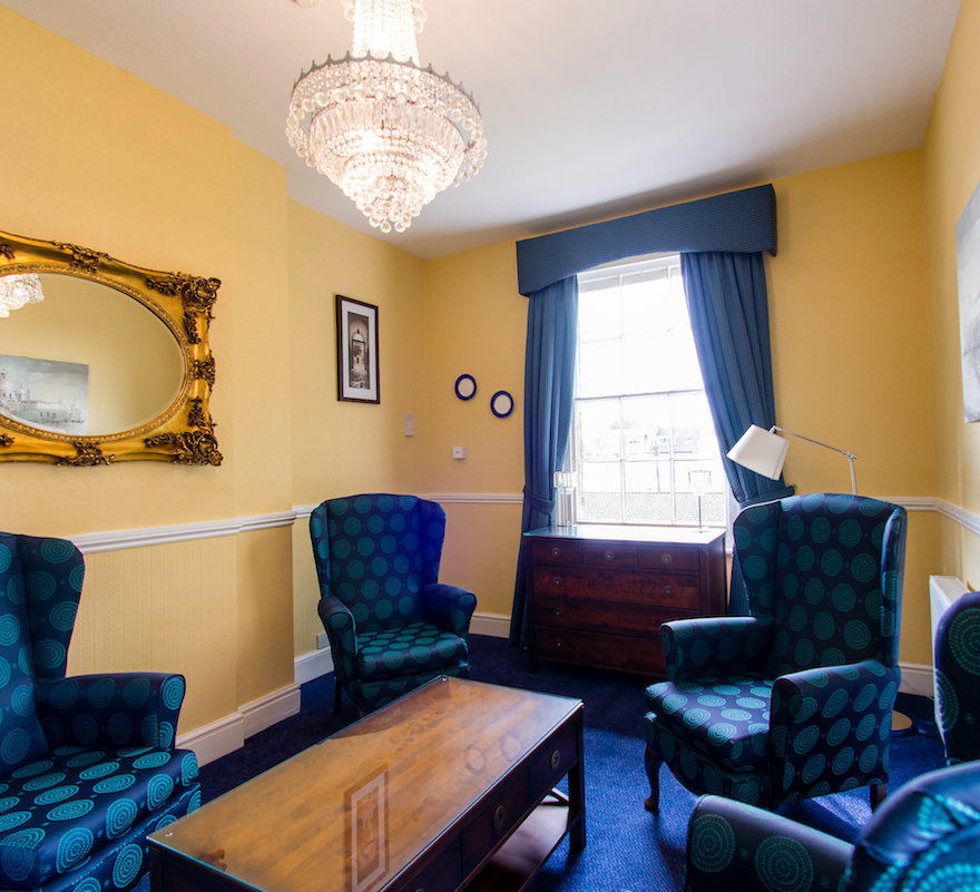 Lounge area with blue carpet, arm chair and curtains