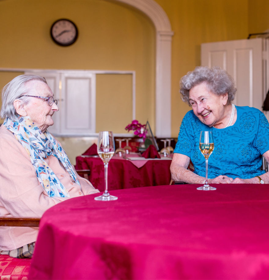 Elderly residents chatting over a glass of wine