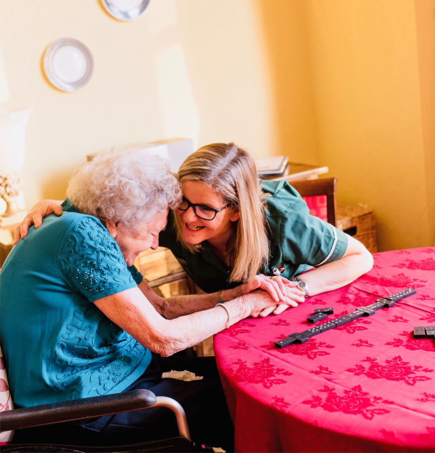 Elderly resident embracing middle aged woman