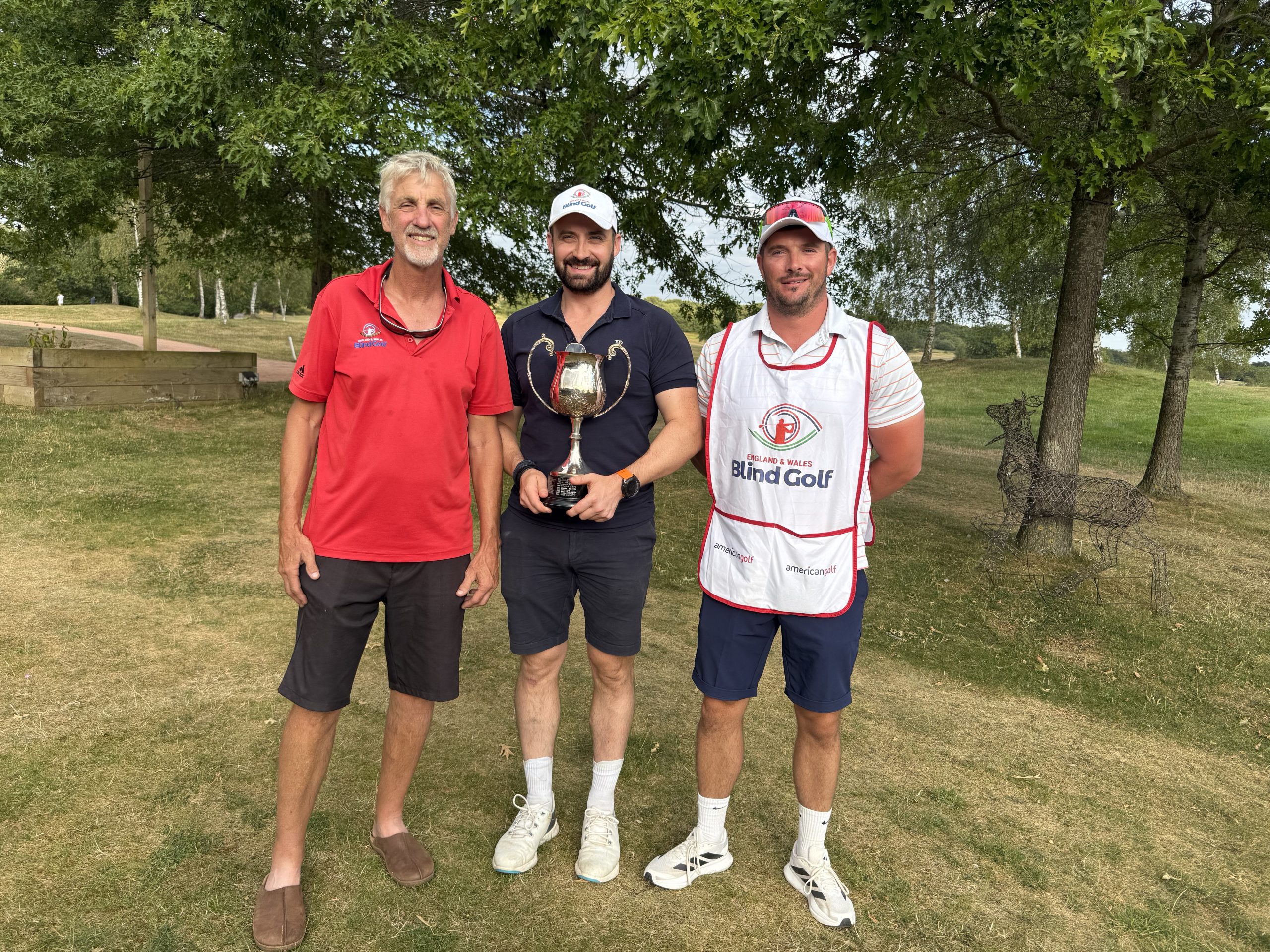Image shows Nick and his Guide with h stroke play trophy accompanied by Vice Captain Mark Macdonald