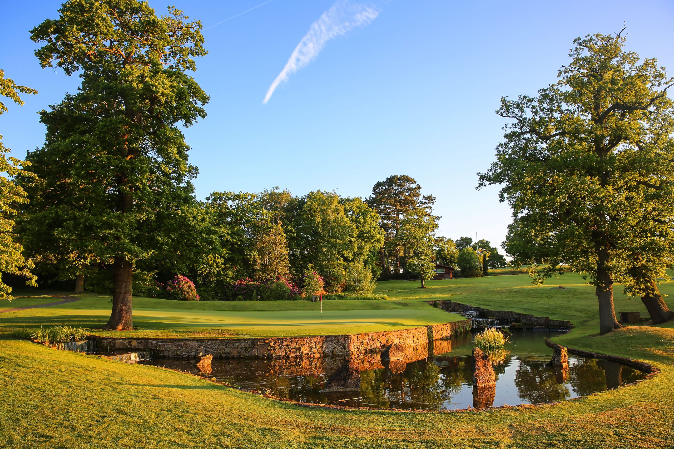 Photo shows a large pond with green trees and fairways. Part of the 14th hole at Portal