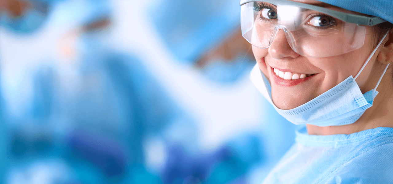 leende läkare i operationskläder, visir och munskydd