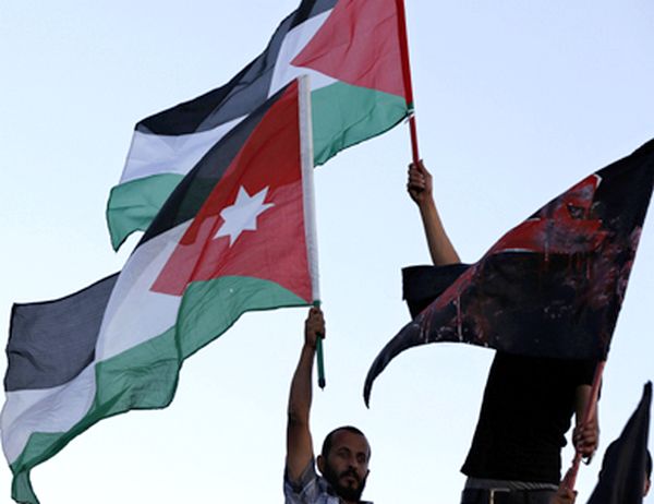 Members of Al-Abbad hold Palestinian and Jordanian national flags, and flag read "Gaza" during a rally in Amman
