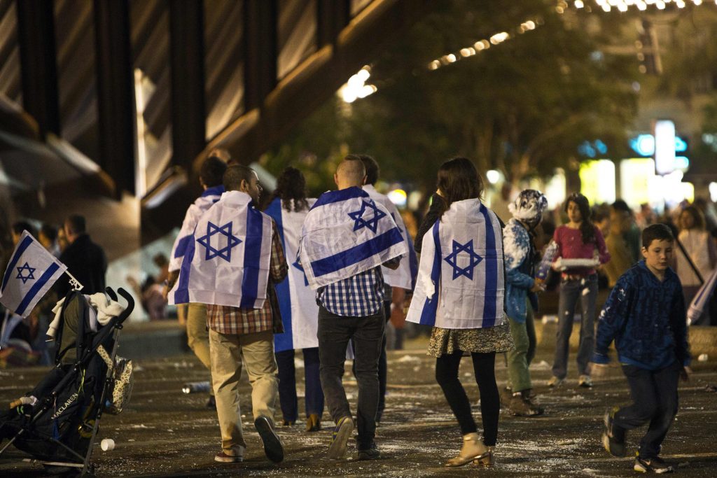 People covered with Israeli national flags walk onto Rabin square to take part in the celebrations for Israel's Independence Day at its 65th anniversary of the creation of the state in Tel Aviv