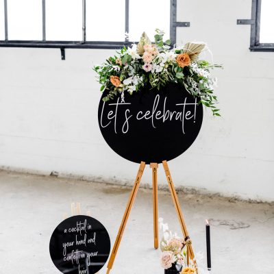 welkomsbord lets celebrate plexiglas zwart schildersezel huren bruiloft rond bord witte letters kalligrafie