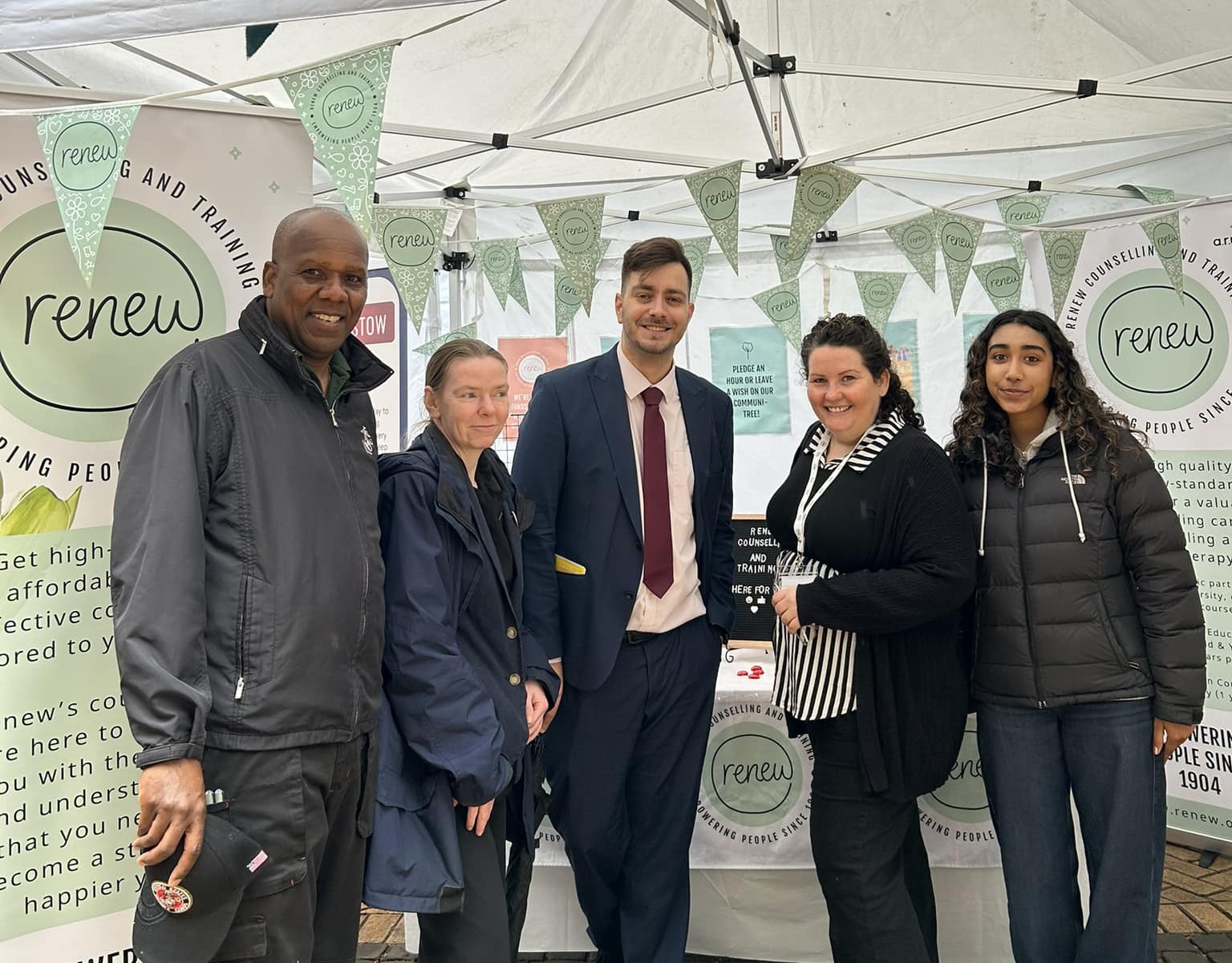 County Hotel staff pose with Renew staff at a pop-up event. Renew bunting and banners hang in the background.