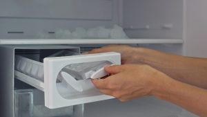 Woman hands taking ice cubes from fridge close up