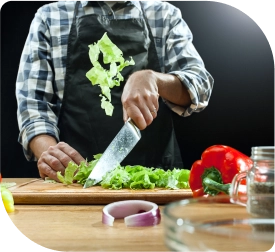 Afbeelding van een man die groenten snijdt op een snijplank