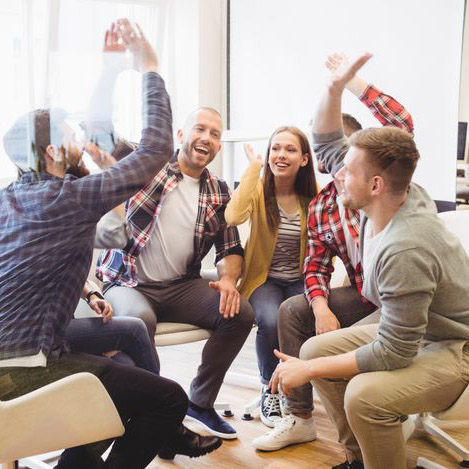 En arbetsgrupp som ger varandra high fives och arbetar som ett team. Det kan du också lära dig med coachning och mental träning för ledare och medarbetare.