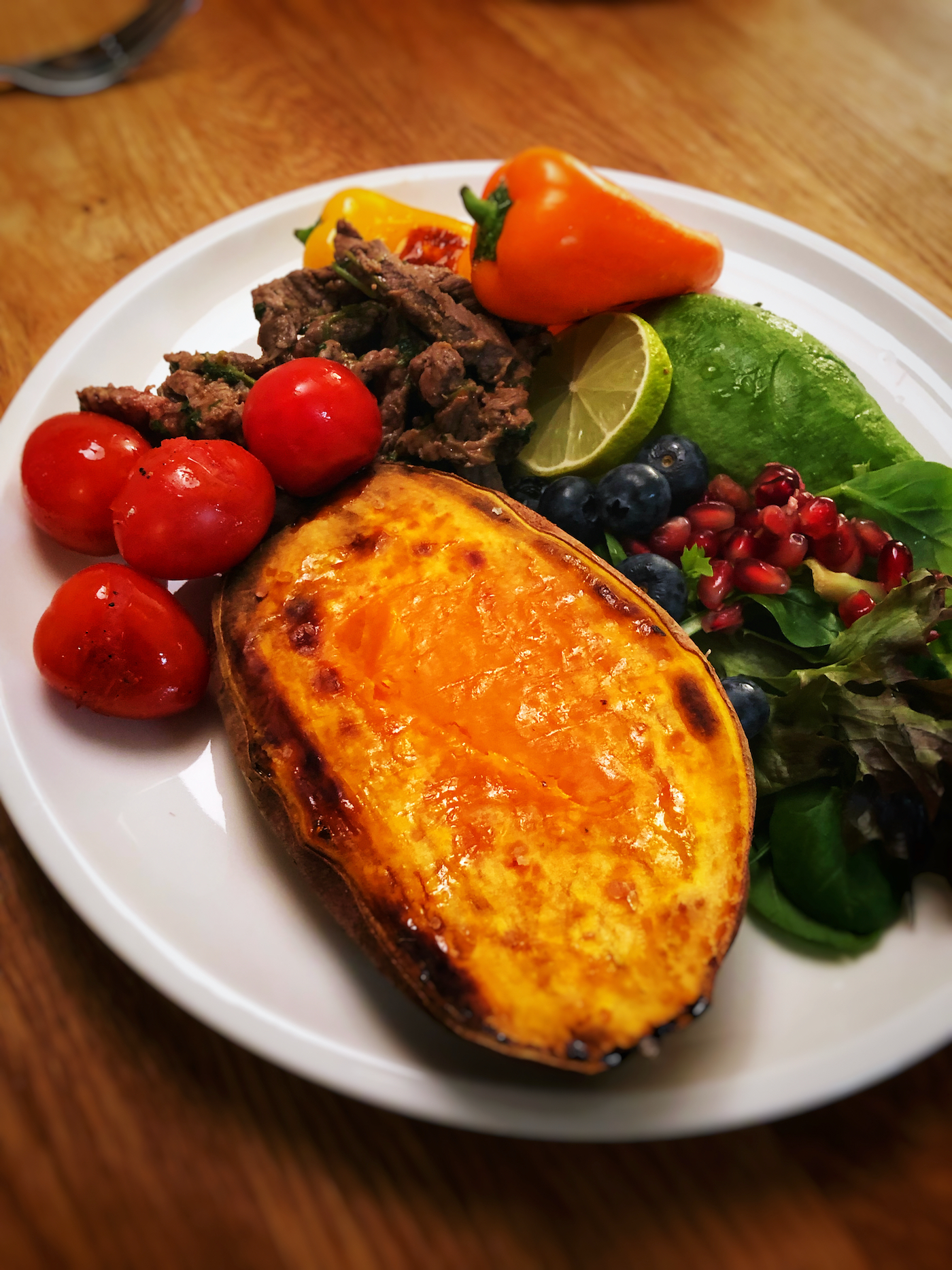 Cilantro fried beef slices with baked sweet potato, blueberries and pomegranate