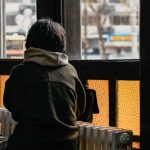 back view shot of a person standing near a glass window