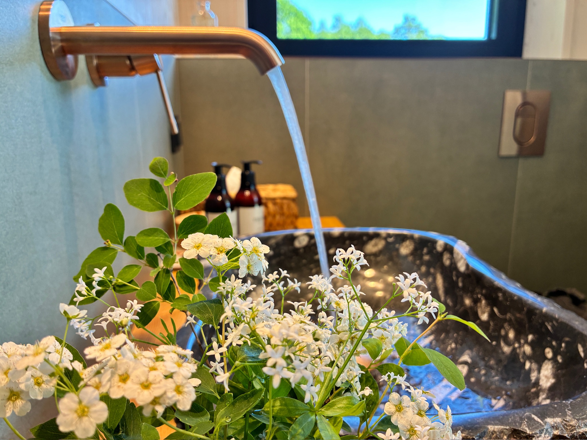 Brass tap and wildflowers in the stone sink at Glass Hut Lysa