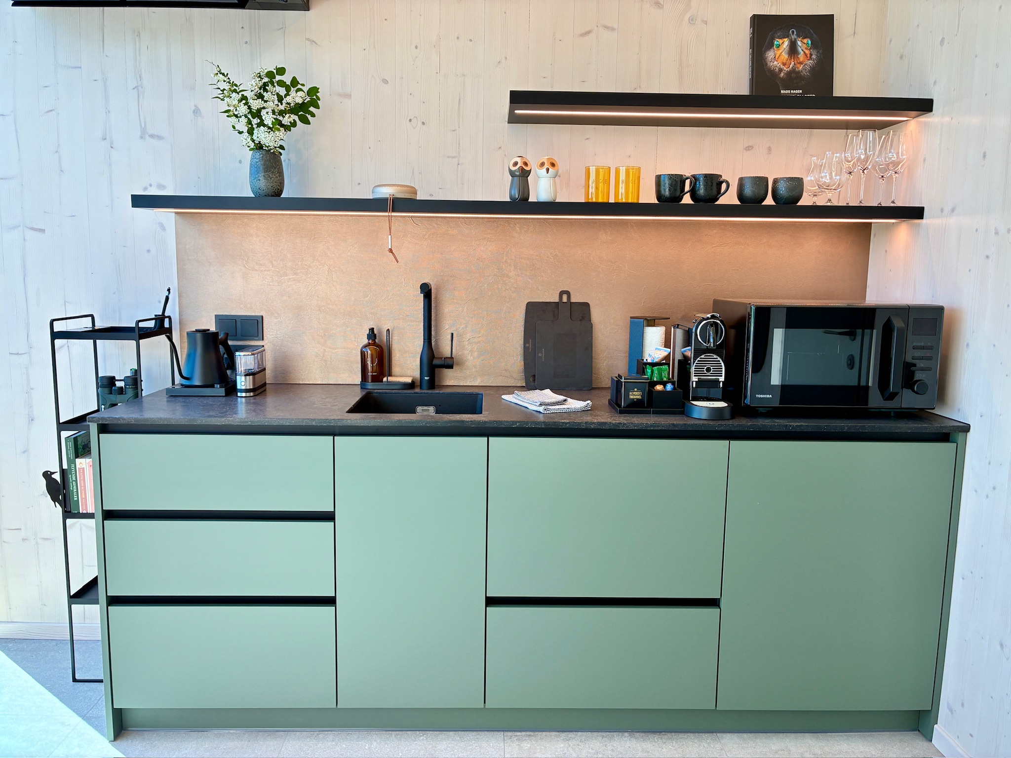 Green kitchenette cabinetry inside Glass Hut Lysa