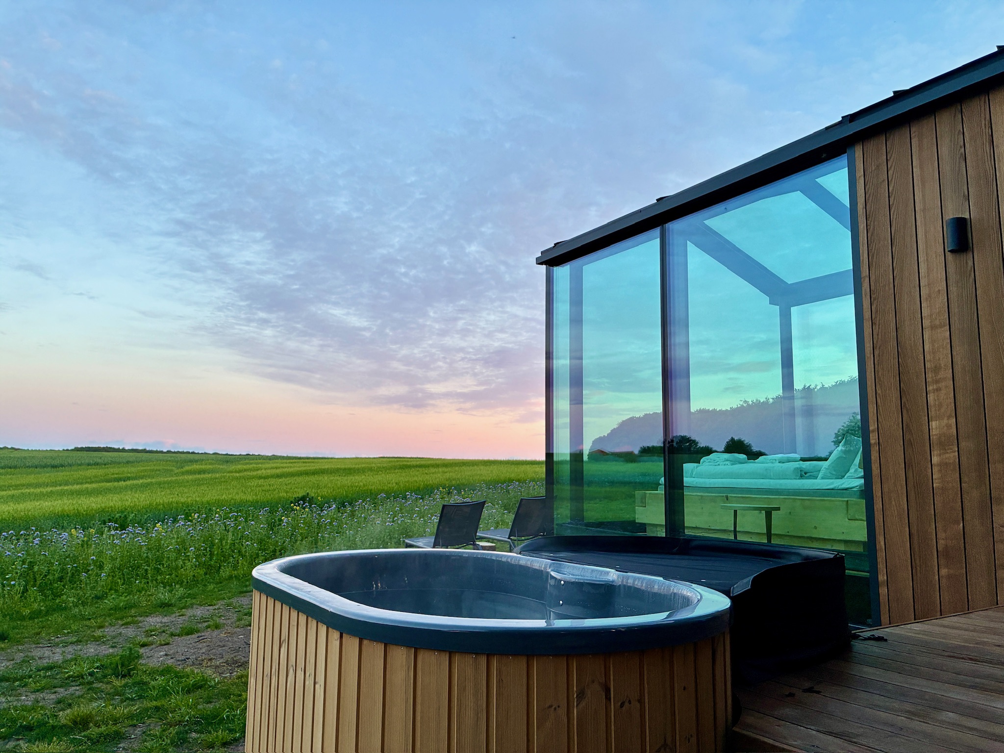 Glass Hut Lysa surrounded by trees and wildflowers on Lolland