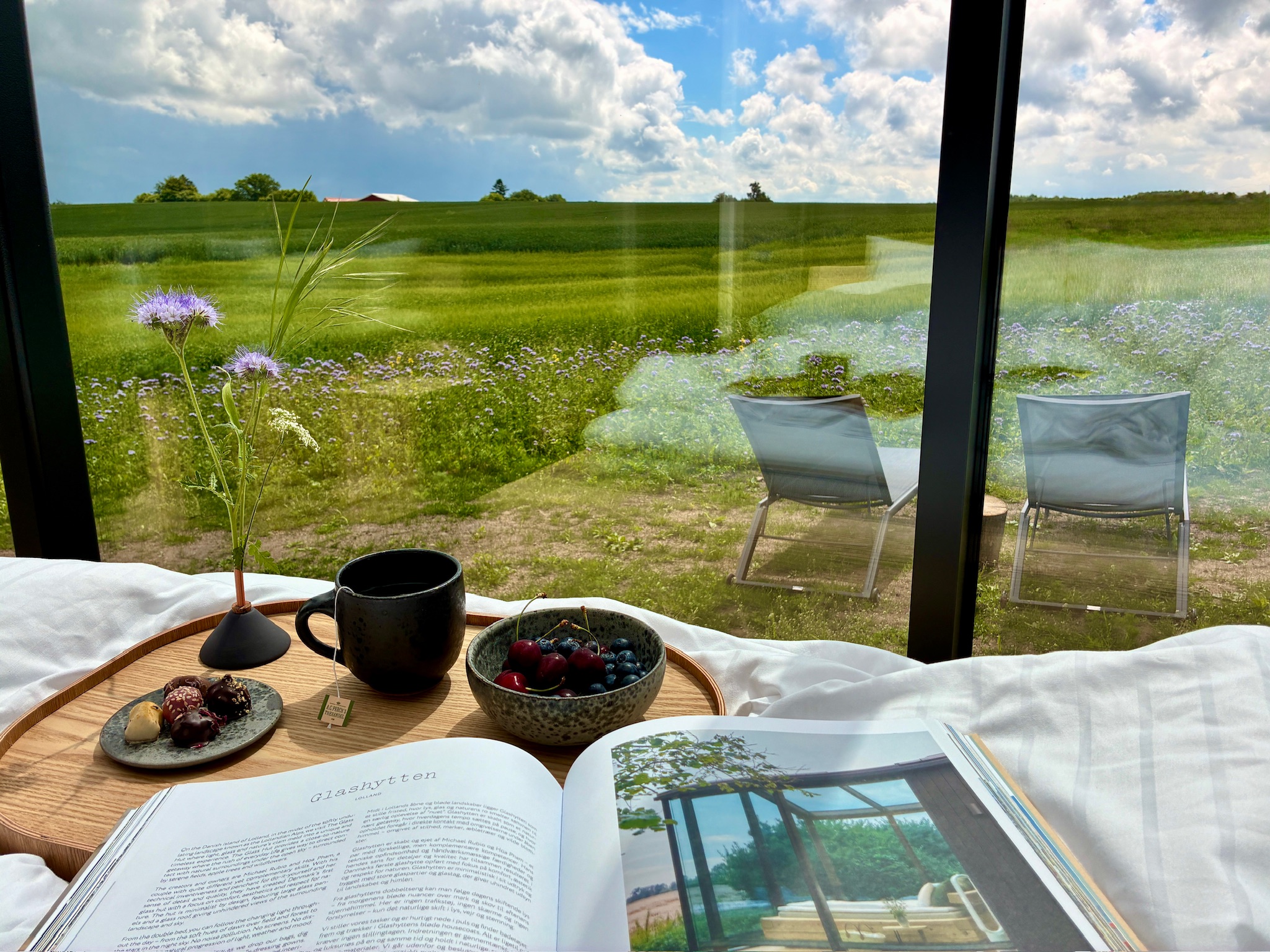 Breakfast tray in bed at Glass Hut Lysa overlooking a wildflower meadow