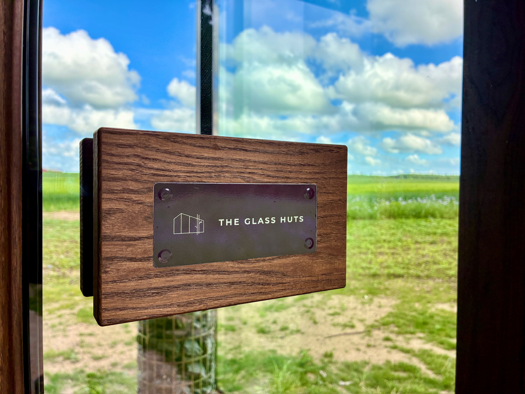 The Glass Huts sign mounted against a bright summer sky