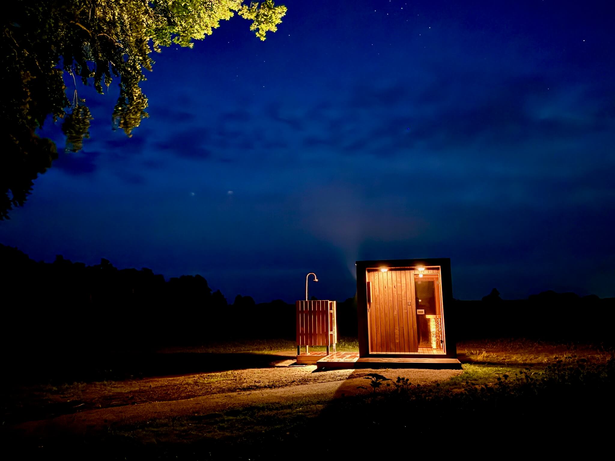 Udendørs sauna og bruser oplyst om natten nær Glashytten Mira