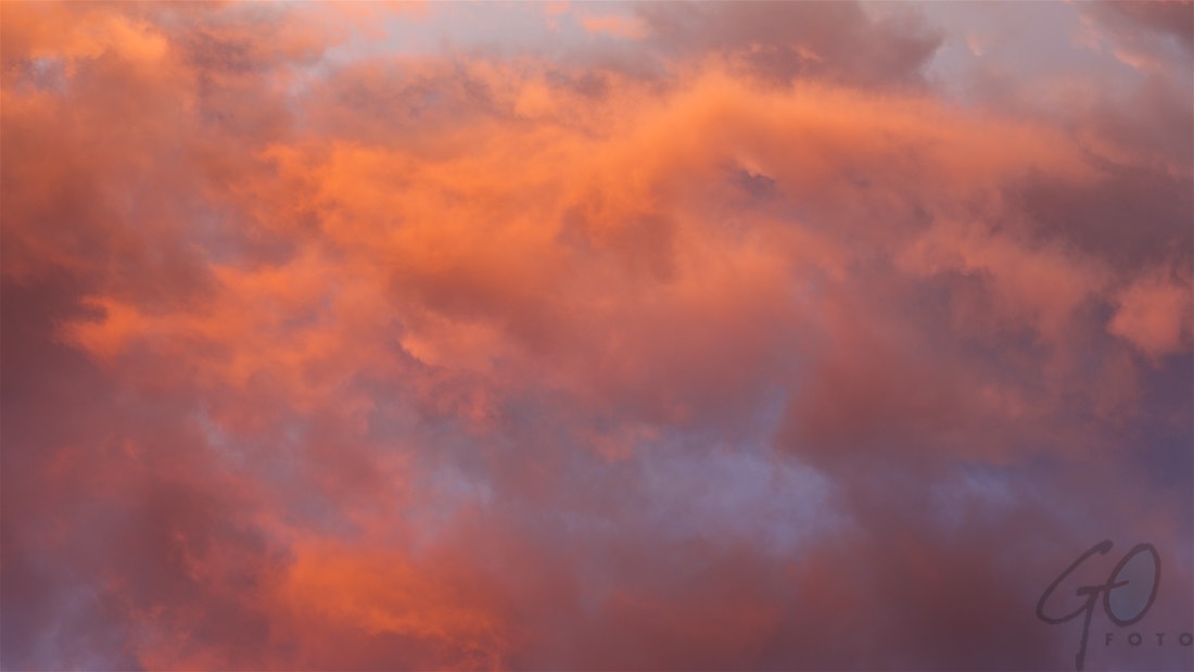 Wolkenman. Foto van een dreigende lucht met oranjerode tekening.