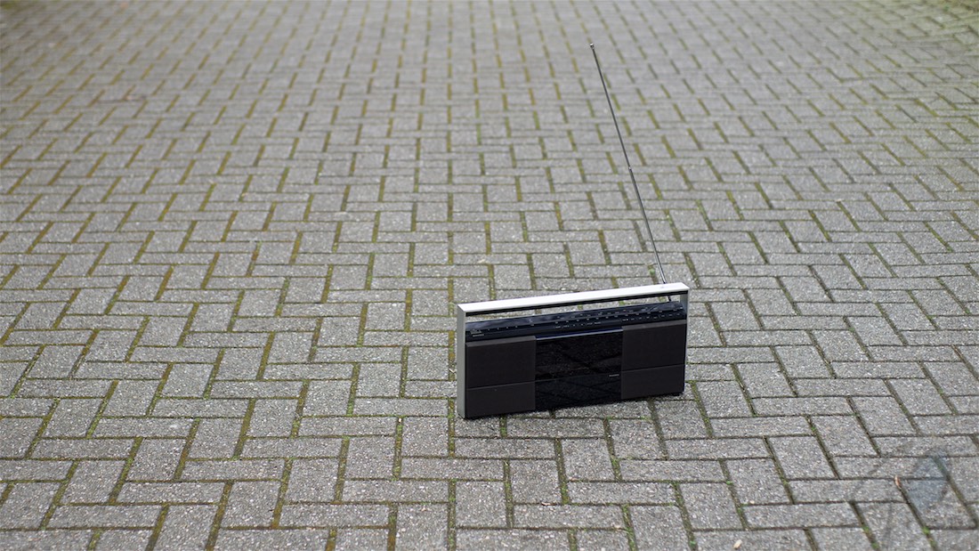 Radio is een vriendje. Foto van een transistorradio op een klinkerweg.