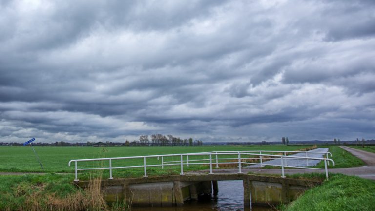 Bruggetje in de polder met dreigende wolkenlucht