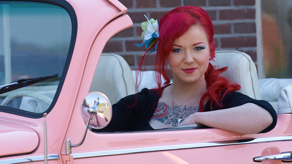 Meisje met rood haar in een roze VW cabrio