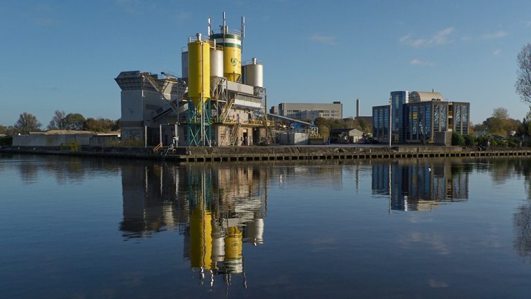 Spiegeling van cementfabriek in water