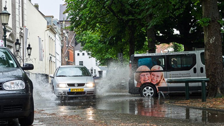 Auto rijdt door waterplas